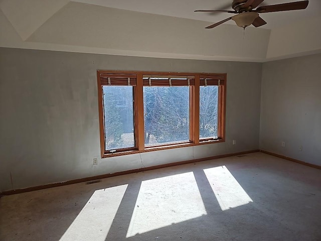 empty room featuring a ceiling fan, lofted ceiling, baseboards, and visible vents