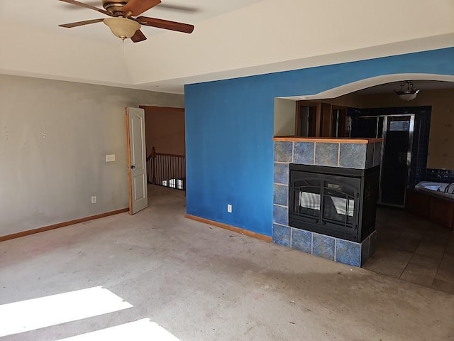 unfurnished living room with a tile fireplace, a ceiling fan, and baseboards