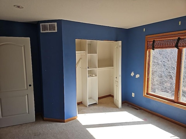 unfurnished bedroom with a closet, visible vents, carpet flooring, and baseboards