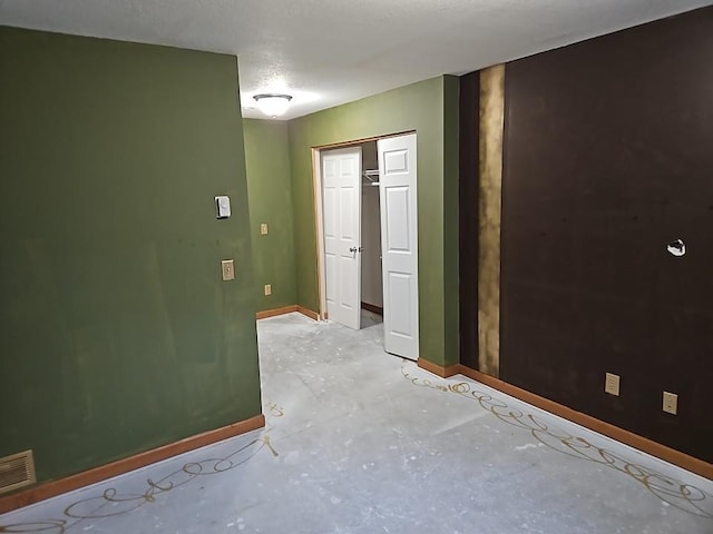 spare room featuring visible vents, concrete floors, and baseboards