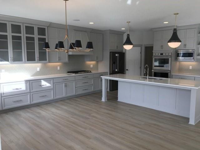 kitchen featuring gray cabinets, appliances with stainless steel finishes, light countertops, and light wood-style floors