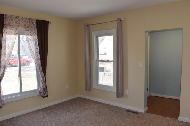 carpeted empty room with visible vents and baseboards