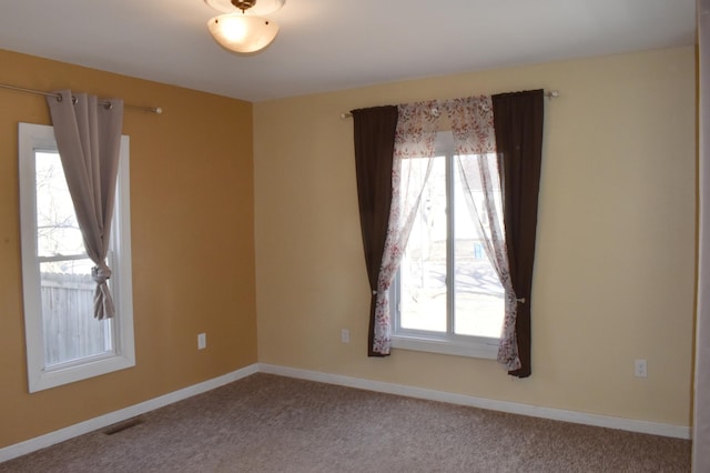 unfurnished room with a wealth of natural light, baseboards, and carpet floors