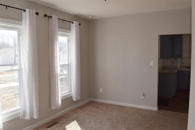 empty room with baseboards, light carpet, and a healthy amount of sunlight