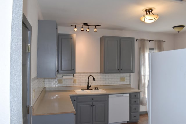 kitchen featuring a sink, white appliances, tasteful backsplash, and light countertops