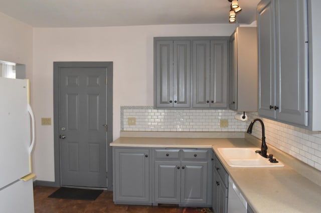 kitchen with gray cabinets, a sink, backsplash, white appliances, and light countertops