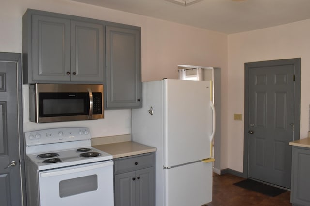 kitchen with white appliances, light countertops, gray cabinets, and baseboards