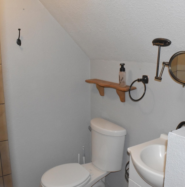 bathroom with vanity, lofted ceiling, toilet, and a textured ceiling