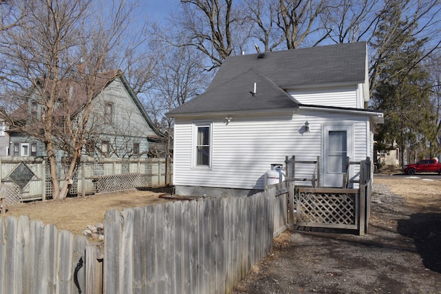 rear view of property featuring roof with shingles and fence