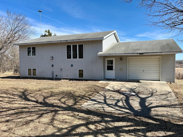 rear view of property with a garage and driveway