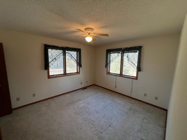 unfurnished room featuring light colored carpet, a textured ceiling, baseboards, and ceiling fan