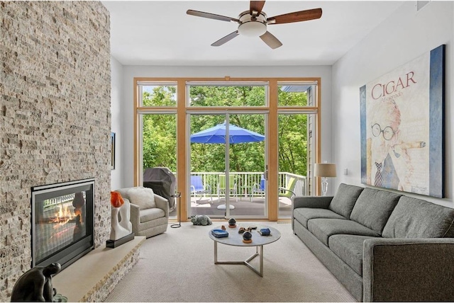 living area with a ceiling fan, carpet, and a fireplace