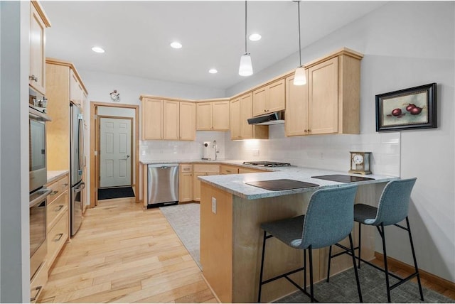 kitchen featuring light brown cabinetry, under cabinet range hood, light wood-type flooring, a peninsula, and stainless steel appliances