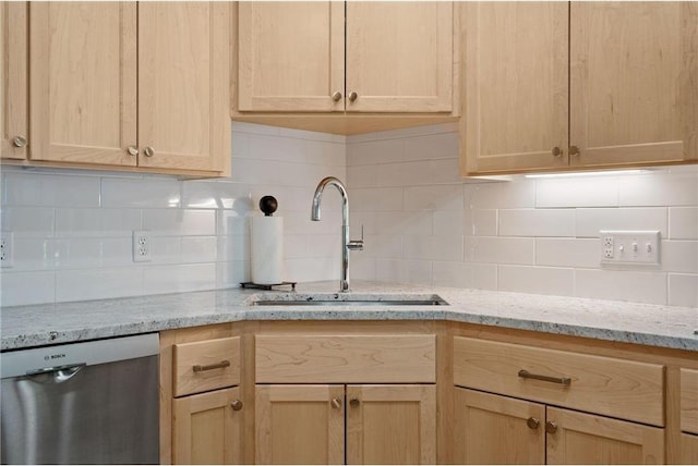 kitchen featuring light stone counters, light brown cabinets, a sink, dishwasher, and backsplash