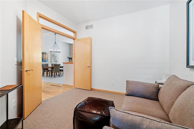 carpeted living room featuring visible vents, baseboards, and an inviting chandelier