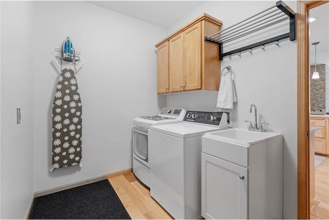 washroom featuring light wood-type flooring, cabinet space, baseboards, and washing machine and clothes dryer