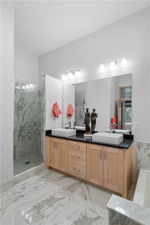 full bath featuring a marble finish shower, marble finish floor, double vanity, and a sink