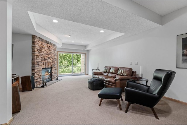 living room featuring a tray ceiling, a textured ceiling, a fireplace, and carpet flooring