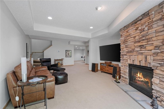 living area featuring a fireplace, baseboards, carpet floors, and a textured ceiling