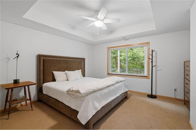 bedroom featuring a tray ceiling, baseboards, and carpet