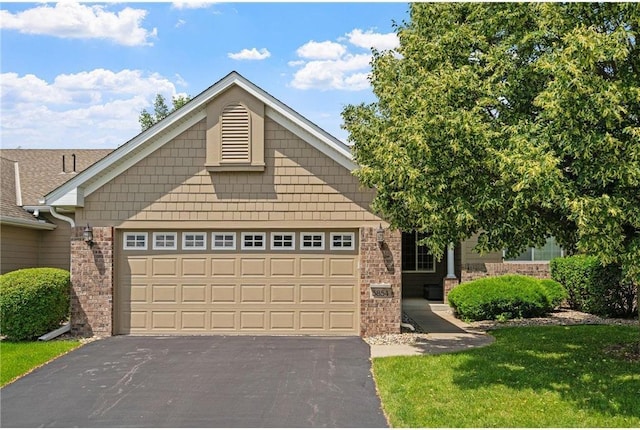 view of front of home with aphalt driveway, brick siding, and an attached garage