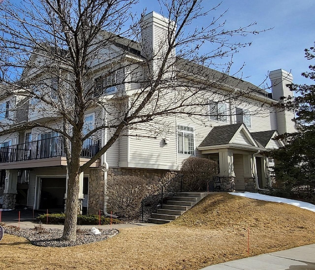 view of front of home featuring stone siding, stairway, and a chimney