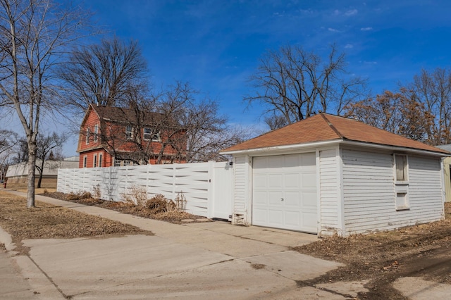 detached garage featuring driveway and fence