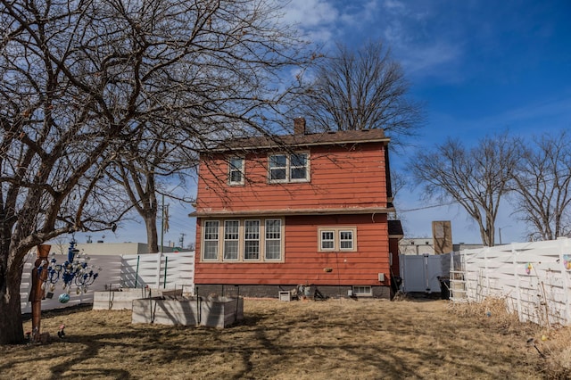 rear view of house featuring a fenced backyard and a chimney