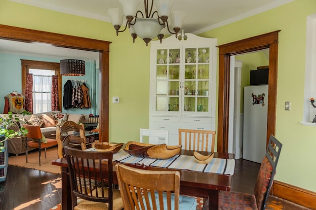 dining area featuring crown molding, an inviting chandelier, and wood finished floors