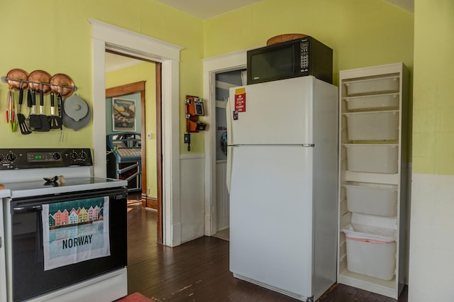 kitchen featuring black microwave, dark wood finished floors, electric range oven, and freestanding refrigerator