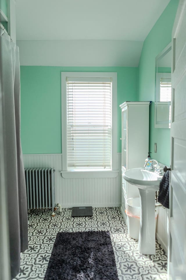 full bath with a shower with curtain, lofted ceiling, radiator heating unit, and a wainscoted wall