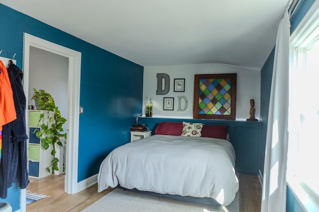 bedroom with vaulted ceiling, baseboards, and wood finished floors