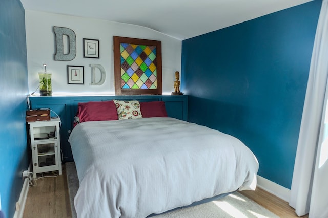 bedroom featuring baseboards, lofted ceiling, and wood finished floors