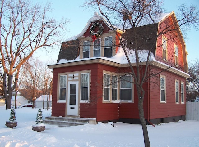 view of front of property featuring a gambrel roof, entry steps, and fence