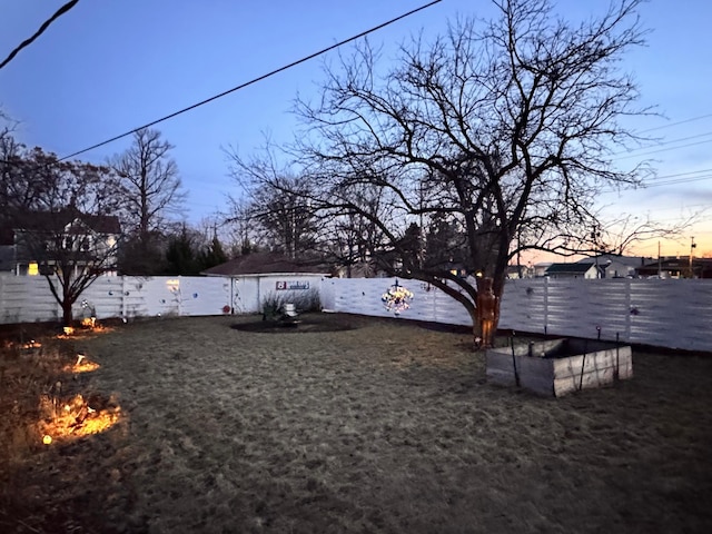 view of yard featuring a fenced backyard and a fire pit