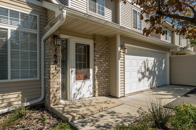 doorway to property featuring a garage, stone siding, and driveway