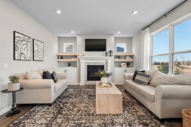 living room with dark wood finished floors, a glass covered fireplace, recessed lighting, and baseboards