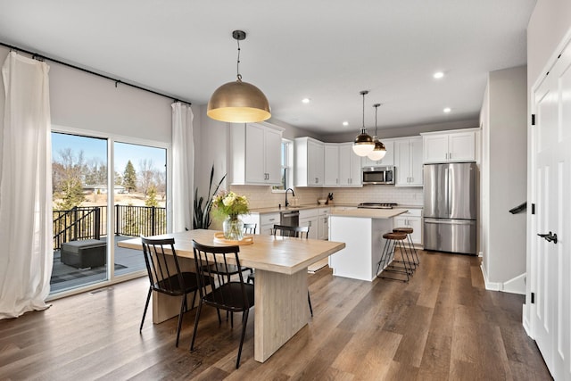 kitchen with a breakfast bar, a sink, a kitchen island, appliances with stainless steel finishes, and light countertops