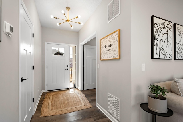 foyer with dark wood finished floors, visible vents, a chandelier, and baseboards