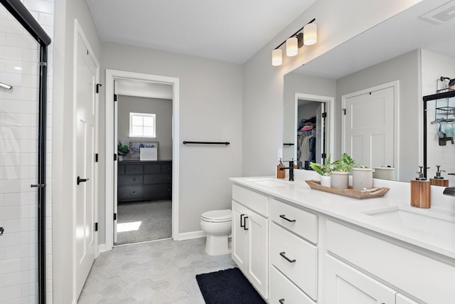 bathroom featuring tiled shower, double vanity, a sink, a spacious closet, and toilet