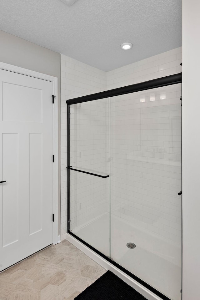 bathroom with a shower stall and a textured ceiling