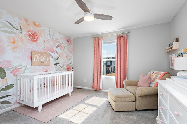 carpeted bedroom with baseboards, a nursery area, and a ceiling fan