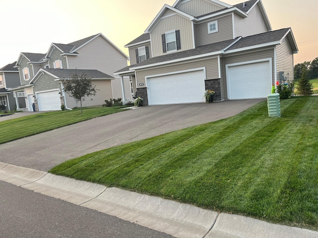 view of front of home featuring a yard, board and batten siding, an attached garage, and aphalt driveway