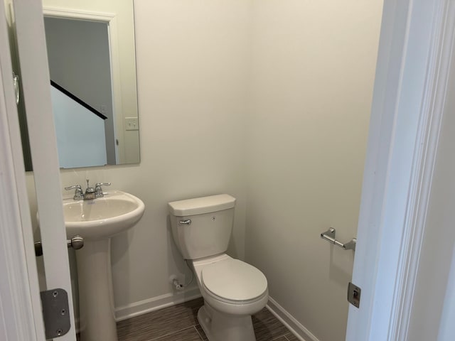 bathroom featuring a sink, baseboards, toilet, and wood finished floors