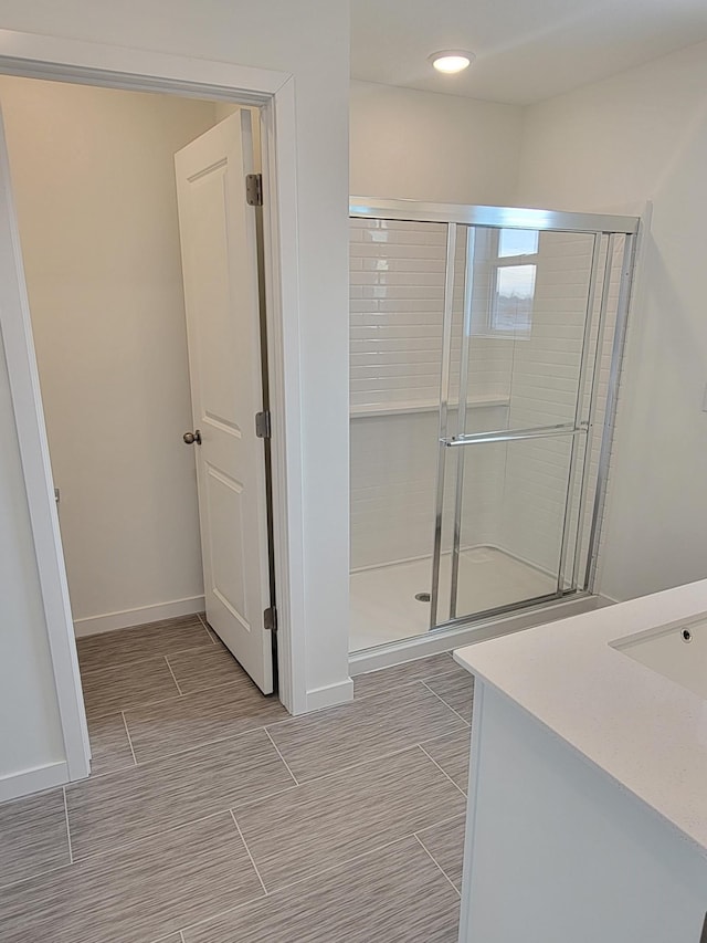 bathroom featuring vanity, baseboards, and a stall shower