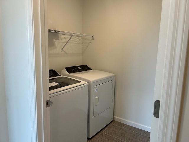 laundry room featuring dark wood finished floors, laundry area, baseboards, and washer and clothes dryer