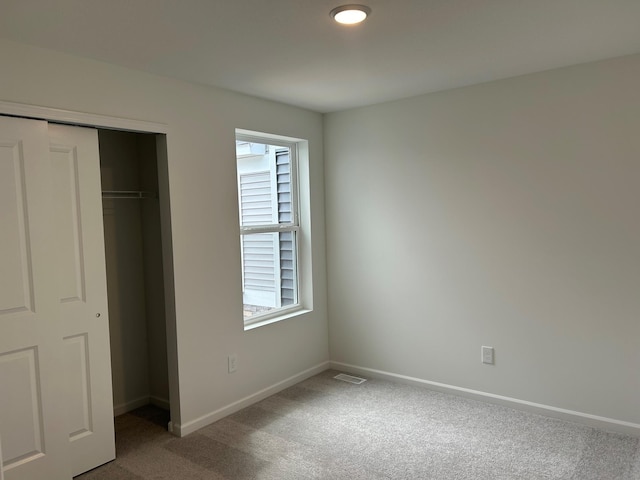 unfurnished bedroom with carpet flooring, visible vents, baseboards, and a closet