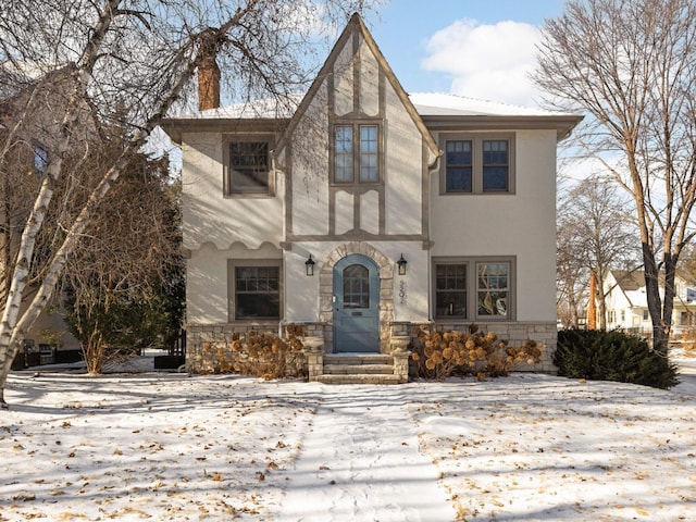 english style home featuring stucco siding and stone siding