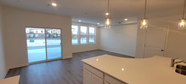 kitchen featuring open floor plan, pendant lighting, light countertops, white cabinets, and dark wood-style flooring