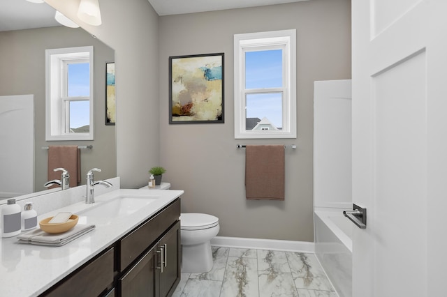 bathroom featuring vanity, baseboards, toilet, marble finish floor, and a washtub